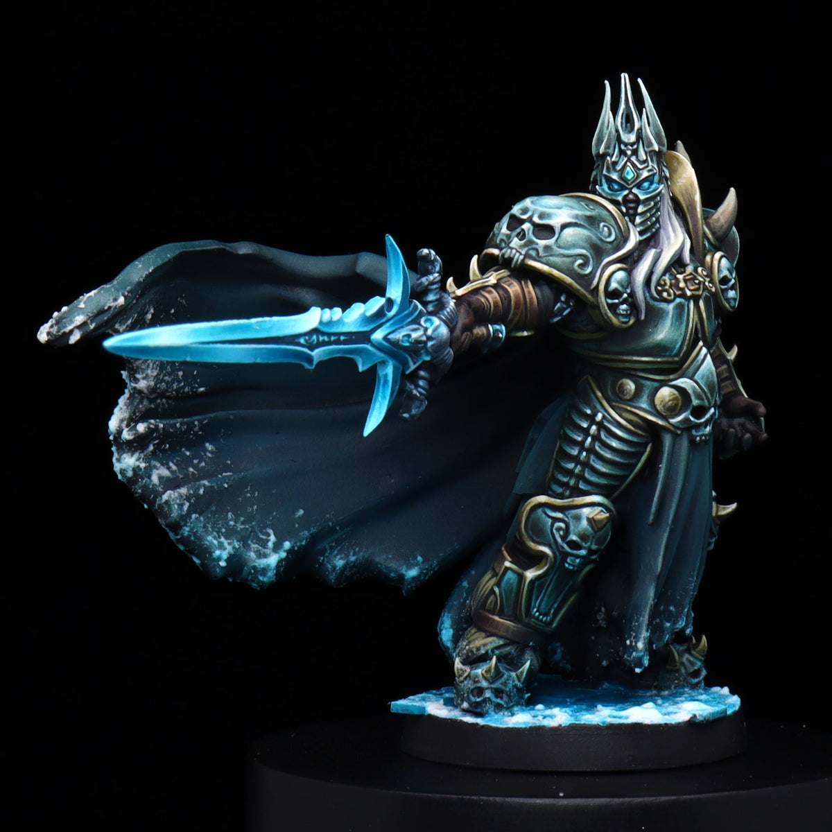 A painted fantasy miniature figurine of an armored warrior holding a glowing blue sword, displayed on a black pedestal against a black background.
